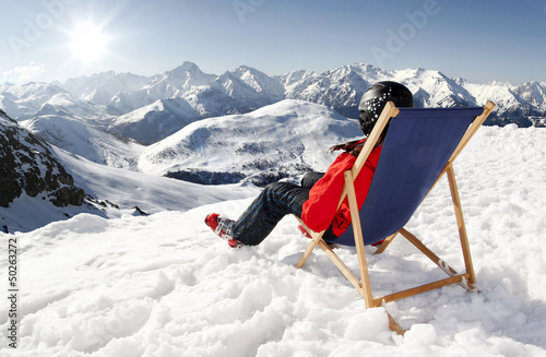 Photo: Women at mountains in winter lies on sun-lounger Women at mountains in winter lies on sun-lounger