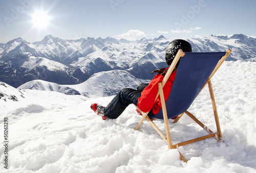 Photo: Women at mountains in winter lies on sun-lounger Women at mountains in winter lies on sun-lounger