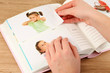 Photos in hands and photo album on wooden table