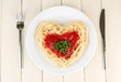 Cooked spaghetti carefully arranged in  heart shape and topped