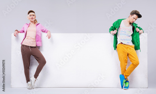 Photo: Cheerful hip-hop young friends with empty board Cheerful hip-hop young friends with empty board