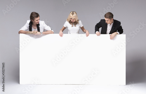 Photo: Small group of friends having fun with empty board Small group of friends having fun with empty board