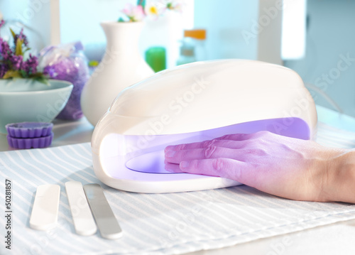 Photo: Nail salon, a female hand inside drying UV light machine Nail salon, a female hand inside drying UV light machine