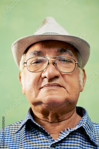 Photo: Portrait of serious old man with hat looking at camera Portrait of serious old man with hat looking at camera