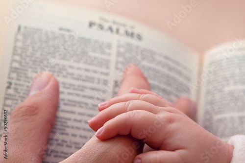 Photo: Baby Holding Dad’s Finger on Bible Baby Holding Dad’s Finger on Bible