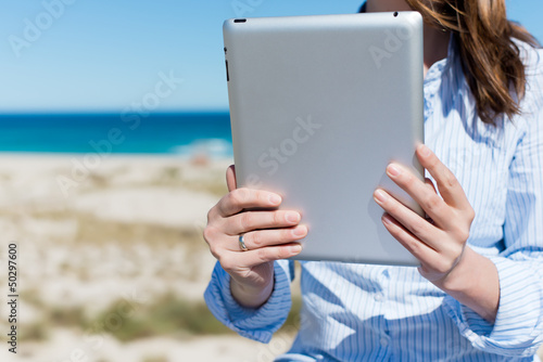 Photo: frau liest mit tablet am strand frau liest mit tablet am strand