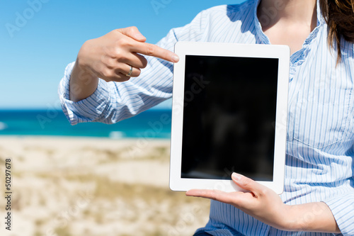 Photo: frau am strand zeigt auf tablet-pc frau am strand zeigt auf tablet-pc