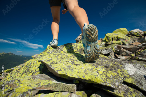 Photo: Hiker jumps over stones in Carpathian mountains with foot closeu Hiker jumps over stones in Carpathian mountains with foot closeu