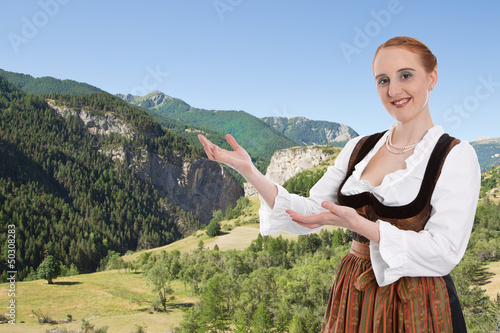 Photo: Frau im Dirndl präsentiert Bayern mit Hintergrund Berge Frau im Dirndl präsentiert Bayern mit Hintergrund Berge
