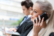 Businesswoman talking on smart phone at meeting.
