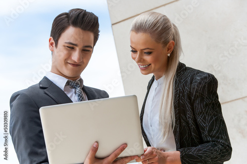 Photo: Satisfied business partners reviewing work on laptop. Satisfied business partners reviewing work on laptop.