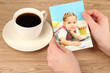 Photo in hands and cup of coffee on wooden table