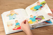 Photos in hands and photo album on wooden table