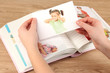 Photos in hands and photo album on wooden table
