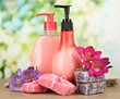 Liquid and hand-made soaps on wooden table, on green background