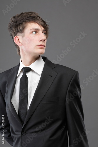 Photo: young businessman black suit casual tie on gray background young businessman black suit casual tie on gray background