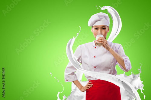 Photo: Asian female cook against milk splashes Asian female cook against milk splashes
