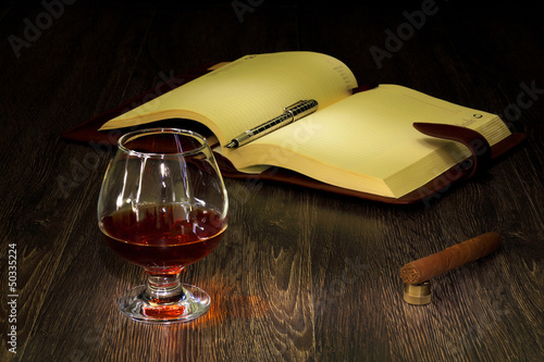 Photo: Cognac, cigar and an old book nearby Cognac, cigar and an old book nearby