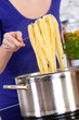 female hands raising cooked pasta out of the pot