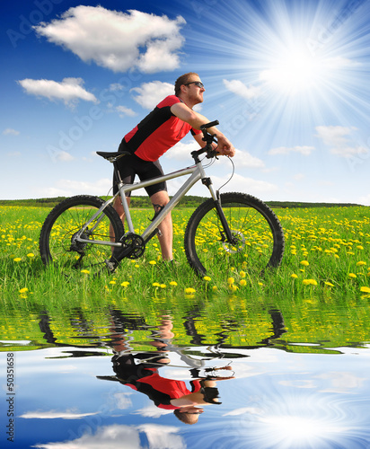 Photo: biker with the mountain bike in the dandelion field biker with the mountain bike in the dandelion field