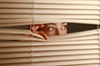 Portrait of a woman looking through out the blinds