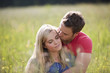 A young couple sitting in long grass embracing