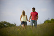 A young couple walking hand in hand through a field
