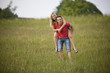A young man giving his girlfriend a piggyback through a field