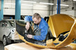 repairman grinding metal body car