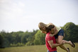 A young couple lifting his girlfriend in a field in summertime