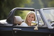 A young woman driving a black sports car
