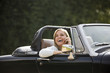 A young woman in a sports car speaking on a mobile phone