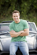 A young man sitting on the bonnet of his black sports car