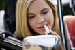 A young woman applying lipstick in a car wing mirror