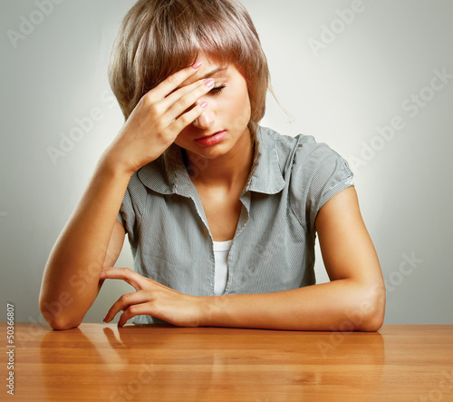 Photo: A young tired woman sitting at the desk A young tired woman sitting at the desk