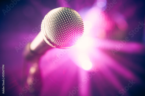 Photo: microphone on stage against purple rays background microphone on stage against purple rays background