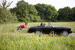 A young man pushing a black sports car
