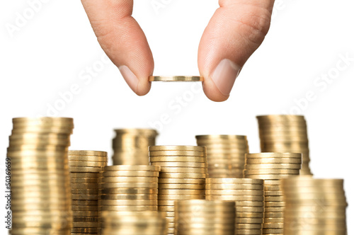 Photo: Close up of male hand stacking gold coins isolated on white Close up of male hand stacking gold coins isolated on white