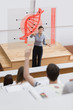 Teacher in front of futuristic interface pointing college studen