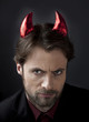 Man in suit with devil horns - concept of nasty boss