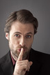Businessman with finger on his lips trying to hide a secret