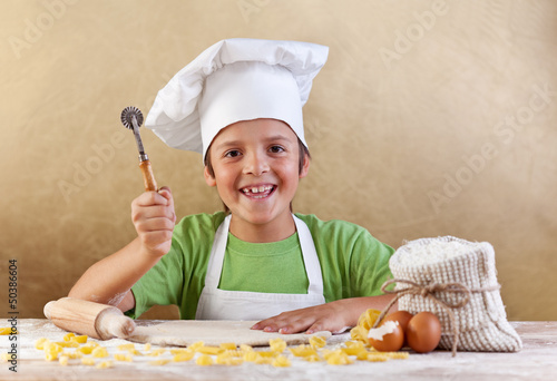 Photo: Happy kid with chef hat making pasta or cookie Happy kid with chef hat making pasta or cookie