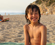 playful boy on the beach with sea on background
