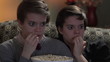 Twin sisters watching a horror movie together, eating popcorn
