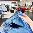 hand holding a new pair of jeans on the background of a supermar