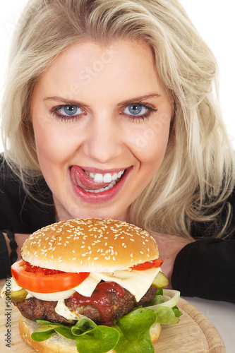 Photo: Hübsche junge Frau mit Hamburger leckt sich den Mund Hübsche junge Frau mit Hamburger leckt sich den Mund