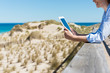 frau am strand schaut auf tablet-pc