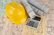 Yellow helmet, calculator and project drawings