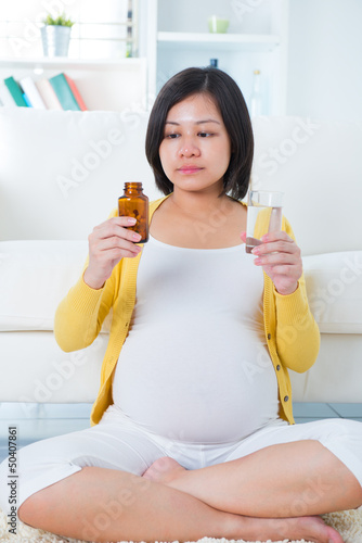 Photo: Pregnant woman taking supplements at home. Pregnant woman taking supplements at home.