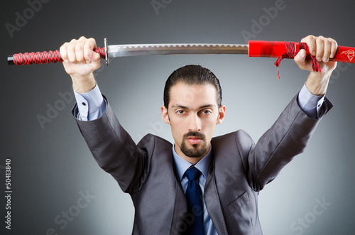 Photo: Angry businessman with sword in dark room Angry businessman with sword in dark room